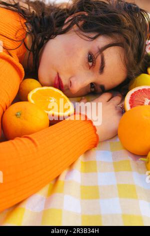 Junge Frau lehnt sich mit Zitrusfrüchten auf den Tisch Stockfoto