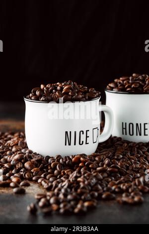 Schwarze Kaffeebohnen Studioaufnahme. Frisch geröstete Kaffeebohnen im Glas. Kaffee in weißen Tassen Stockfoto