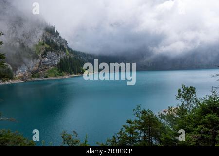 Herrliches touristisches Oeschinnensee mit Wasserfällen und Schweizer Alpen, Kandersteg, Berner Oberland, Schweiz. Stockfoto