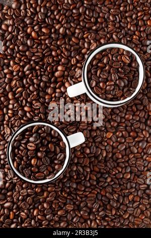 Schwarze Kaffeebohnen Studioaufnahme. Frisch geröstete Kaffeebohnen im Glas. Kaffee in weißen Tassen Stockfoto