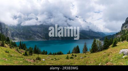 Herrliches touristisches Oeschinnensee mit Wasserfällen und Schweizer Alpen, Kandersteg, Berner Oberland, Schweiz. Stockfoto