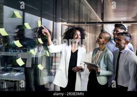 Gruppe von Geschäftsleuten, die Präsentationen mithilfe von Post it durchführen. Geschäftsfrau, die eine Teambesprechung leitet Stockfoto