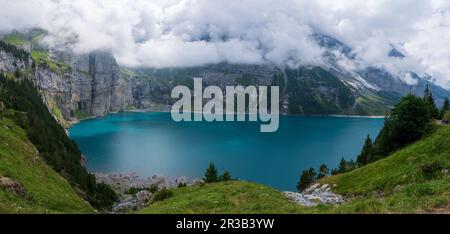 Herrliches touristisches Oeschinnensee mit Wasserfällen und Schweizer Alpen, Kandersteg, Berner Oberland, Schweiz. Stockfoto