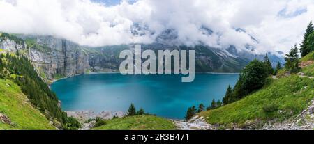 Herrliches touristisches Oeschinnensee mit Wasserfällen und Schweizer Alpen, Kandersteg, Berner Oberland, Schweiz. Stockfoto