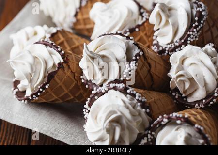 Viele Eiskegel auf einem Holztisch. Weicheis oder gefrorene Vanillesauce in Cones. Waffel-Marshma Stockfoto
