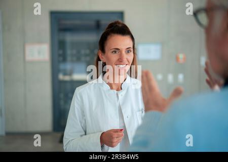 Lächelnder Arzt hört Seniorpatienten im Krankenhaus zu Stockfoto
