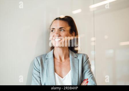 Eine nachdenkliche Geschäftsfrau im Büro, die durch eine Glaswand gesehen wurde Stockfoto