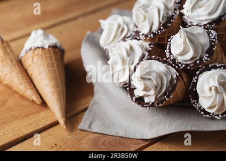 Viele Eiskegel auf einem Holztisch. Weicheis oder gefrorene Vanillesauce in Cones. Waffel-Marshma Stockfoto