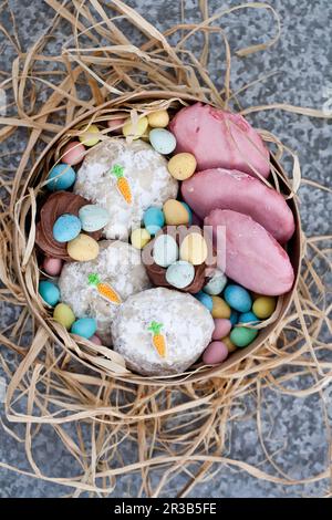 Osterkekse mit Rosa- und Karottendekorationen, Schokoladen-Cupcakes und Mini-Schokoladeneiern Stockfoto