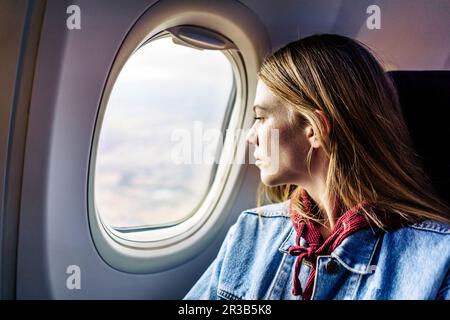 Eine Frau, die aus dem Fenster schaut und im Flugzeug sitzt Stockfoto