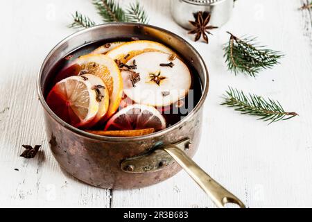 Glühwein mit Obstscheiben und Gewürzen in einem Kupfertopf Stockfoto