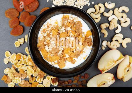 Müsli, Nüsse, Obst, Milch und Haferbrei zum Frühstück. Teller mit Haferflocken, Cashew, Äpfeln und Samen Stockfoto