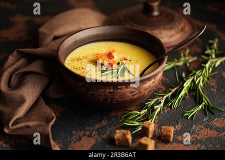 Fischcremesuppe mit Lachs, Käse, Kartoffeln und Kräutern in brauner Keramiksuppenschale. Dunkles Essen Pho Stockfoto