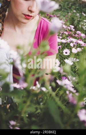 Eine Frau inmitten bunter Gänseblümchen auf dem Feld Stockfoto