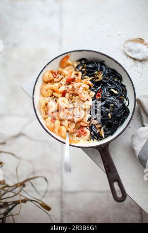 Garnelen in karamellisierten Zwiebeln und Sahne Sauce mit schwarzen Spaghetti Stockfoto