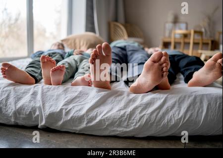 Vater schläft zu Hause mit Söhnen im Bett Stockfoto