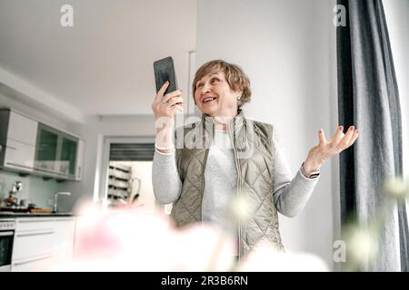 Ältere Frau, die zu Hause Videoanrufe über ein Smartphone führt Stockfoto
