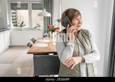 Ältere Frau, die zu Hause auf dem Smartphone spricht Stockfoto