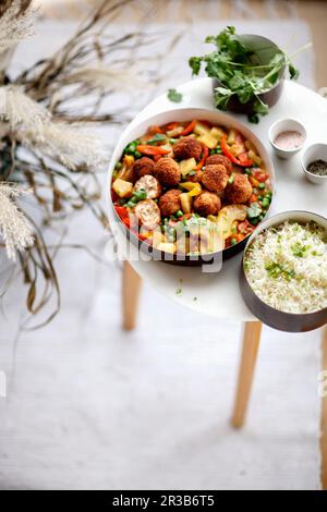 Gebratene Fischbällchen mit grünen Erbsen, Ananasscheiben, süßen Paprika und Koriander Stockfoto