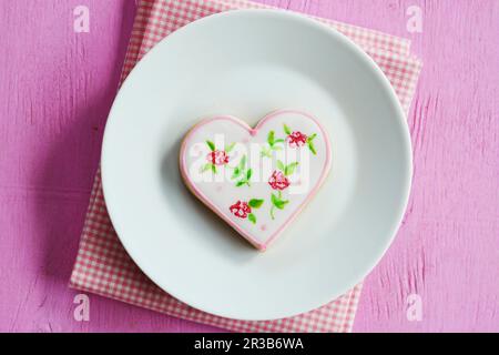 Herzkekse handbemalt mit Blumenmotiven auf einem Teller Stockfoto