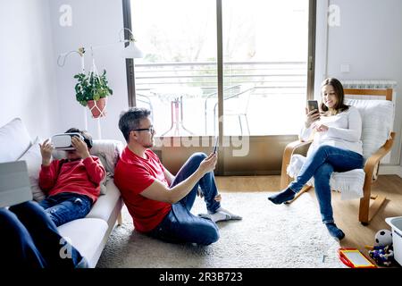 Familie, die zuhause kabellose Technologien im Wohnzimmer nutzt Stockfoto