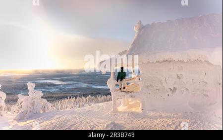 Eine Frau, die im Winter auf der Veranda des Tiefkühlhauses sitzt Stockfoto