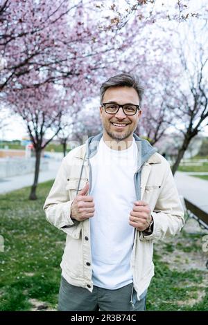 Ein lächelnder Mann mit Brille steht im Park Stockfoto