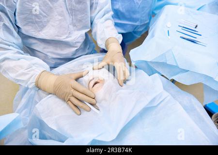 Augenarzt untersucht das Auge des Patienten im Operationssaal Stockfoto