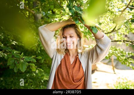 Lächelnde Frau, die einen Zweig des Baumes hält Stockfoto