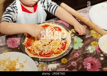 Kinder machen Pizza. Master Class für Kinder zum Kochen von italienischer Pizza. Kleine Kinder lernen, wie man kocht Stockfoto