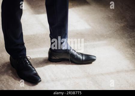 Beine eines Geschäftsmannes, der in der Fabrik in schwarzen, formellen Schuhen steht Stockfoto