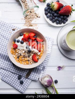 Müsli mit Mandeljoghurt und frischen Beeren, mit Matcha-Tee Stockfoto