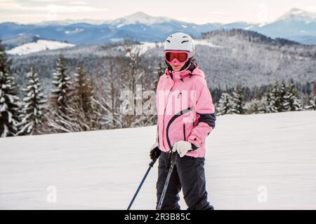 Porträt einer jungen Frau in einem Skioutfit und Helm in den verschneiten Bergen Stockfoto