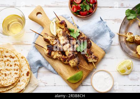 Marinierte Hähnchenspieße mit Koriander, Zitrone und Tomatensalat Stockfoto