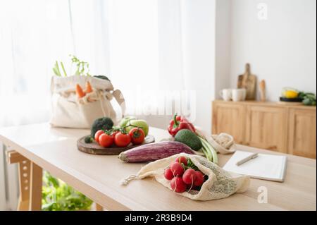 Frischgemüse in wiederverwendbaren Beuteln auf dem Tisch zu Hause Stockfoto