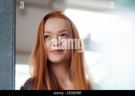Rücksichtsvolle rothaarige Frau, die seitwärts schaut Stockfoto