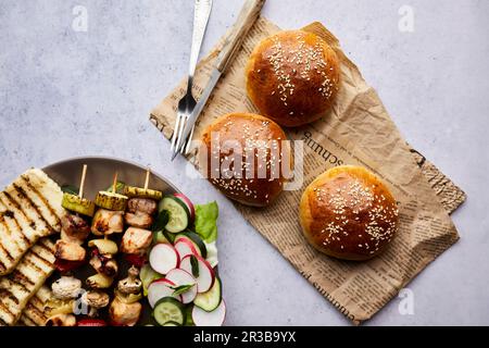 Hausgemachte Brötchen mit Hähnchenspießen, gegrilltem Halloumi-Käse und frischem Salat Stockfoto