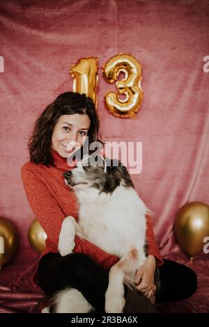 Lächelnde Frau, die mit Border Collie Hund sitzt Stockfoto