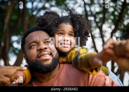 Mann mit Lockenhaar, Huckepack-Tochter Stockfoto