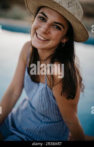 Lächelnde Frau, die am Pool sitzt Stockfoto