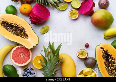 Tropische Früchte liegen flach mit Mango, Papaya, Pitahaya, Passionsfrucht, Trauben, Limetten und Ananas Stockfoto
