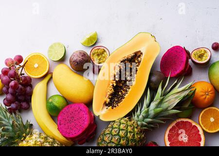 Tropische Früchte liegen flach mit Mango, Papaya, Pitahaya, Passionsfrucht, Trauben, Limetten und Ananas Stockfoto