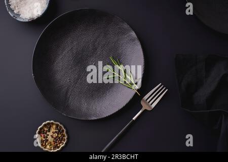 Schwarzes Abendessen - leere Teller auf dunklem Hintergrund Stockfoto