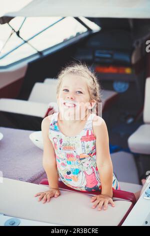 Lustiges kleines Mädchen auf einer Yacht, lachend und mit einem Schnurrbart aus Eis oder Milch herumalbern. Bab Stockfoto