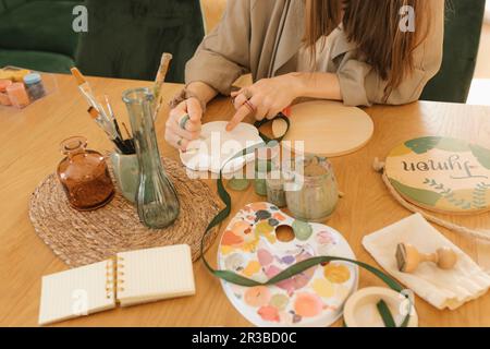 Frau, die am Tisch Farbe in die Palette gießt Stockfoto