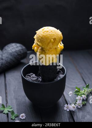 Veganes Mango-Sorbet in einer schwarzen Waffelform Stockfoto