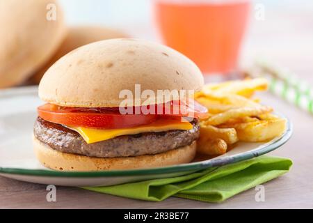 Burger-Sandwich mit Tomaten und Cheddar auf weißem Teller mit gebratenen Kartoffeln Stockfoto