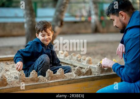Vater und Sohn bauen Sandburgen auf Sandkästen im Park Stockfoto