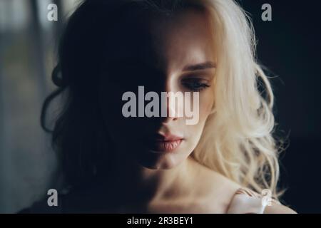 Eine deprimierte blonde Frau in der Dunkelkammer Stockfoto