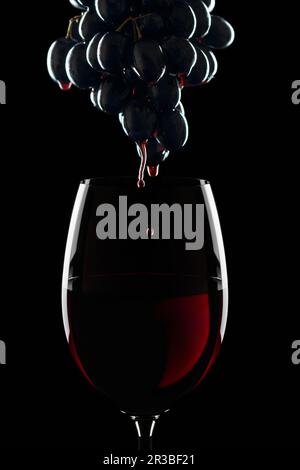 Ein Glas Rotwein und ein paar rote Weintrauben Stockfoto